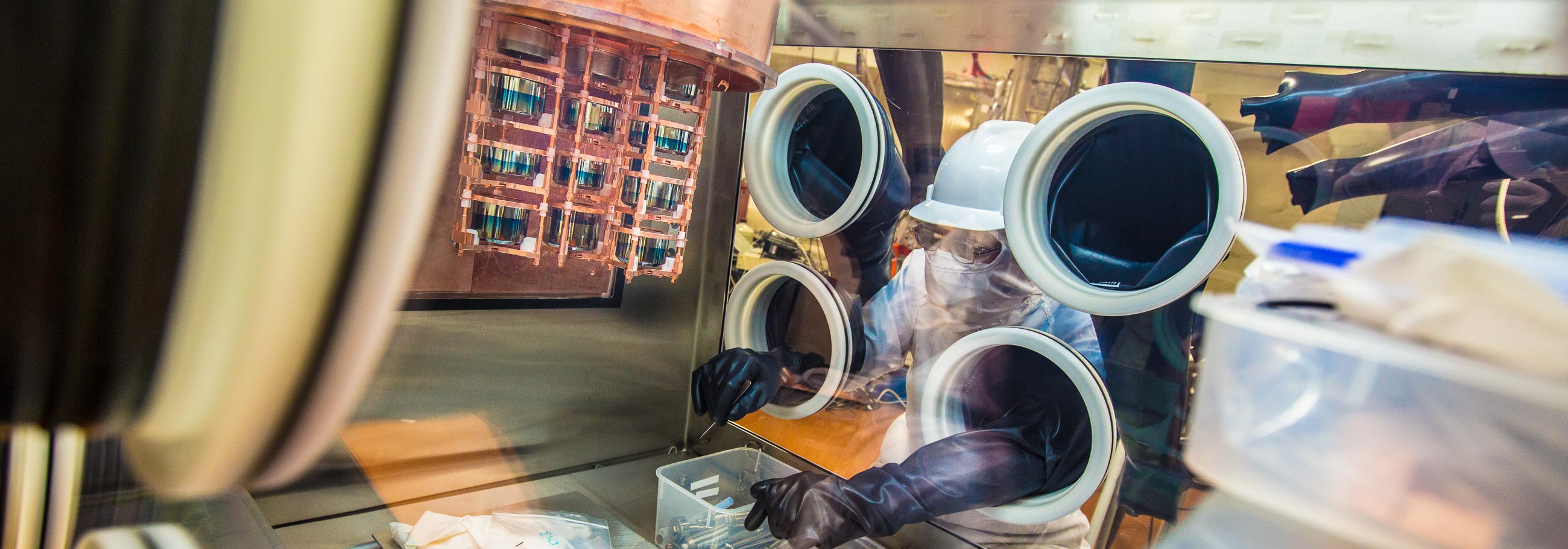 A researcher works on a cryostat inside a glovebox.