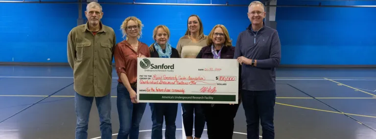 Members of the Lead Community Center Foundation accepted a $100,000 check for the new community center--they are standing inside the Handley Center gym. 