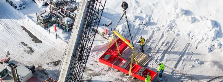 This image shows D&W Crane and Rigging in Rapid City, unloading a large red L-shaped piece of steel that will be used for DUNE at SURF.