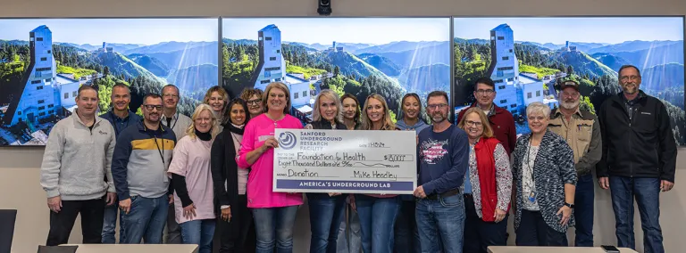 A group photo around a large donation check from SURF to the Foundation for Health