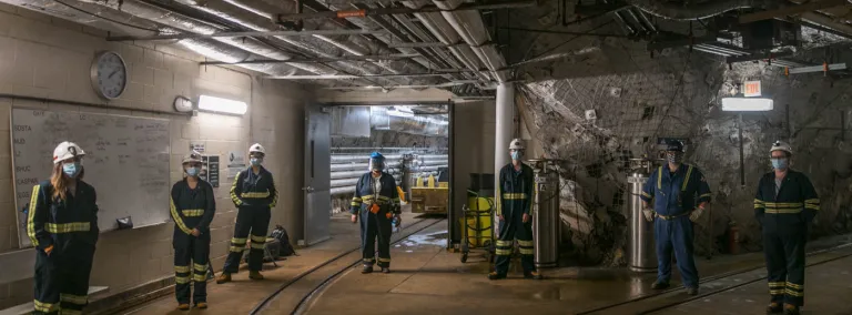 seven people stand 6 feet apart in an underground tunnel