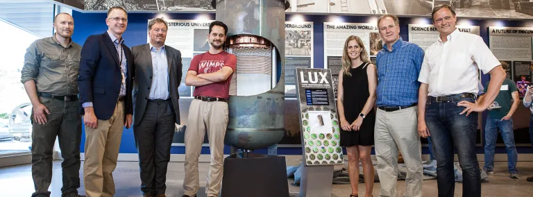 7 people gather around the LUX exhibit.