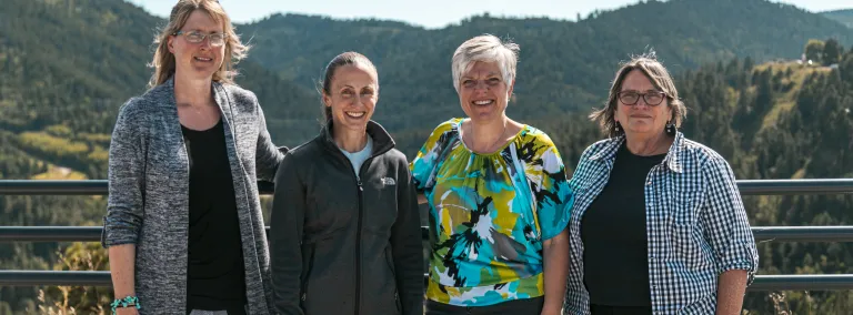 Group photo of four people in front of mountain skyline