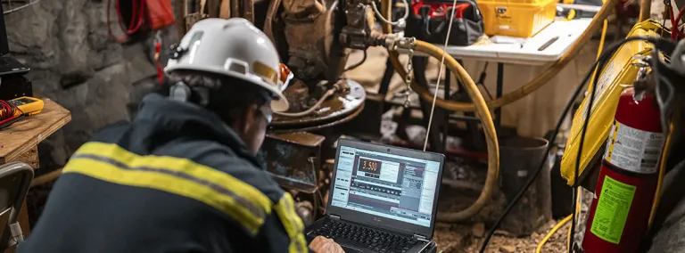 Researcher works on a computer in an underground drift.