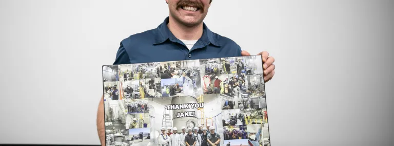 Davis holds a collage of photos with the words "Thank you Jake!" written on it