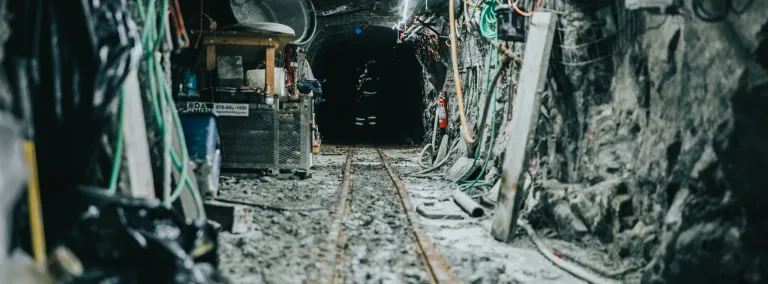 looking down a rocky, lit drift with some equipment on the ground