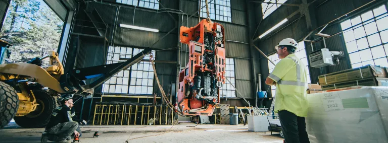 a man watches heavy machinery lifts other heavy machinery