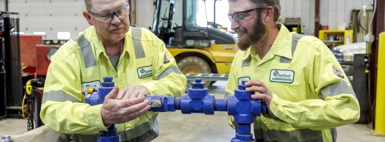 Two workers work on a pump 