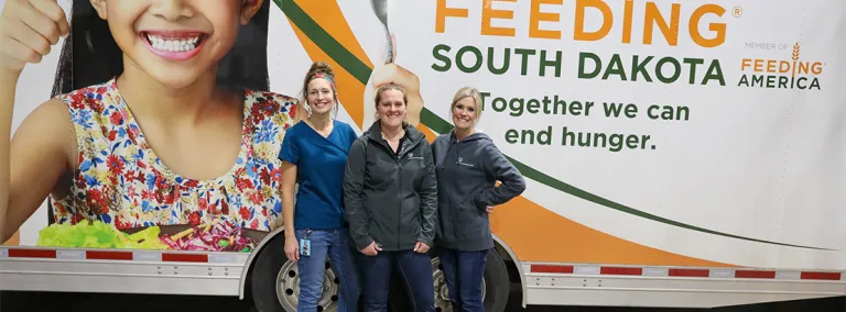 Three people stand in front of the mobile pantry.