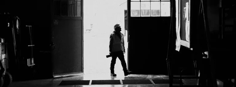 A silhouette of a person with a camera in a large doorway