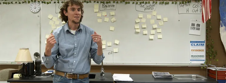 teacher stands at the front of a classroom 