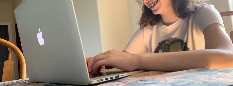 girl smiles while working on computer