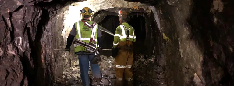 Two workers walk down an illuminated underground tunnel