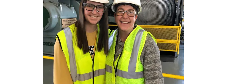 Two people in hardhats stand in the hoistroom.