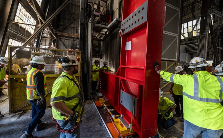 Supported from above by a crane, the L-beam is carefully moved into position by the rigging team for transport down the shaft in Lead, South Dakota. 