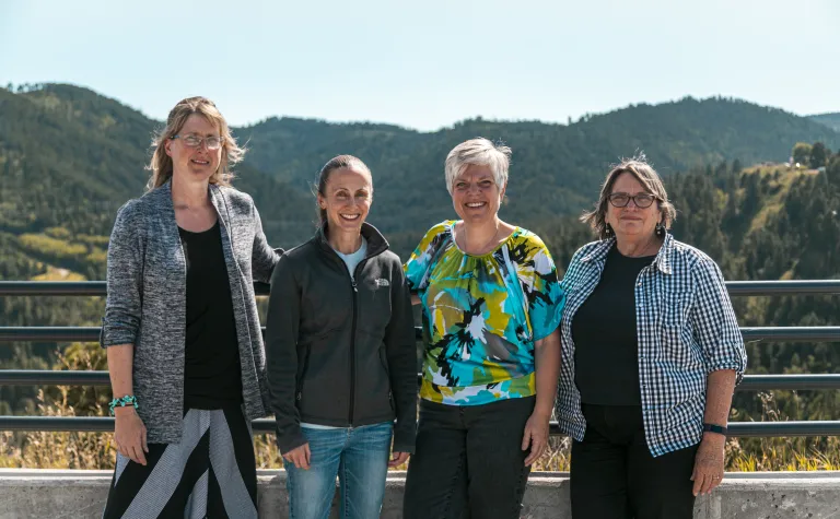 Group photo of four people in front of mountain skyline