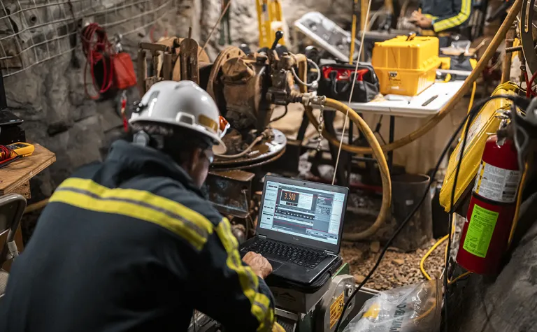 Researcher works on a computer in an underground drift.