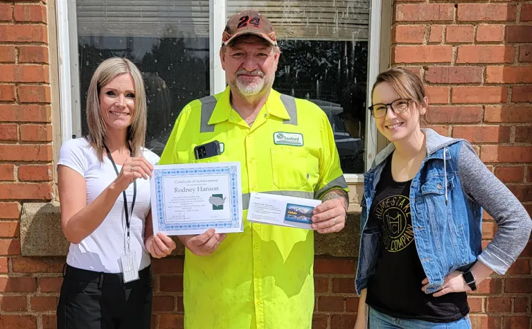 three people hold a certificate 