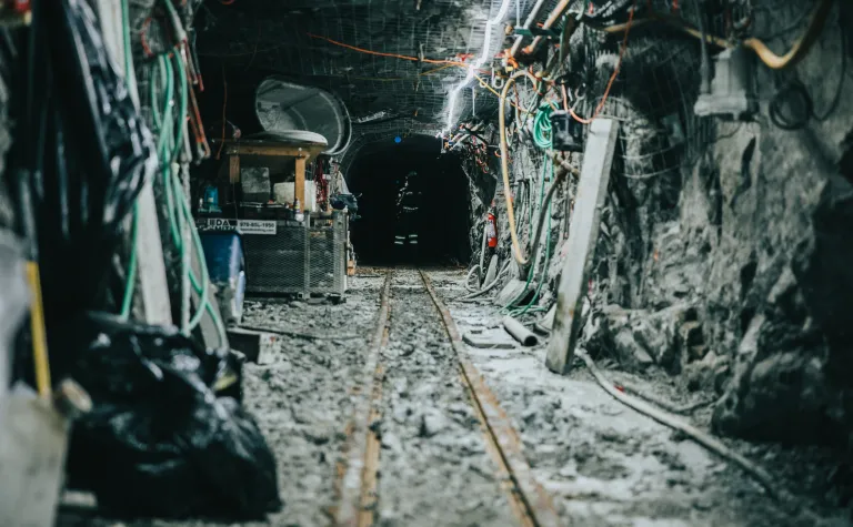 looking down a rocky, lit drift with some equipment on the ground