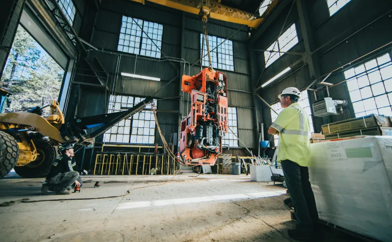 a man watches heavy machinery lifts other heavy machinery