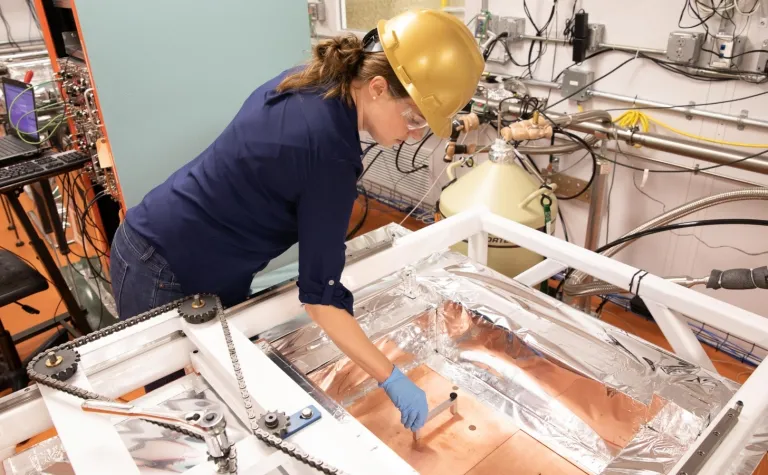 person in a hardhat works on a detector