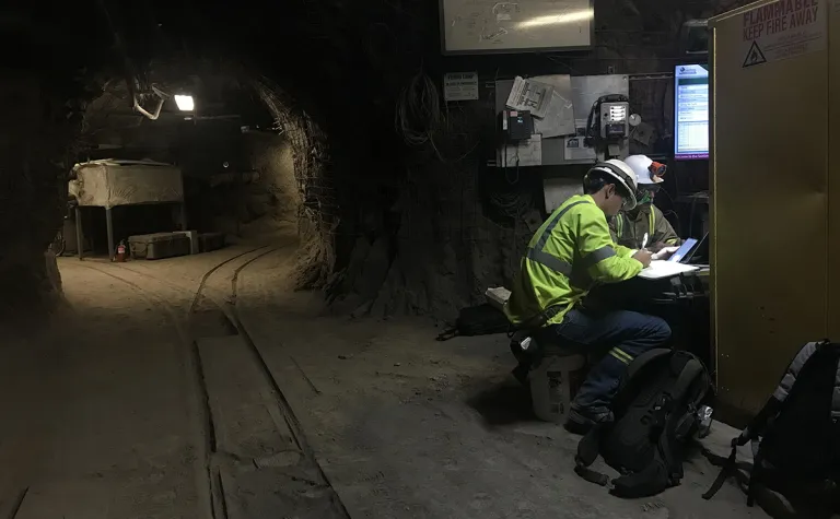 two people in safety gear work in an underground drift 