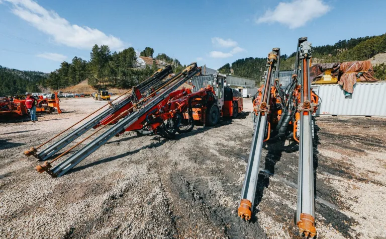 two jumbo drill rigs in a parking lot