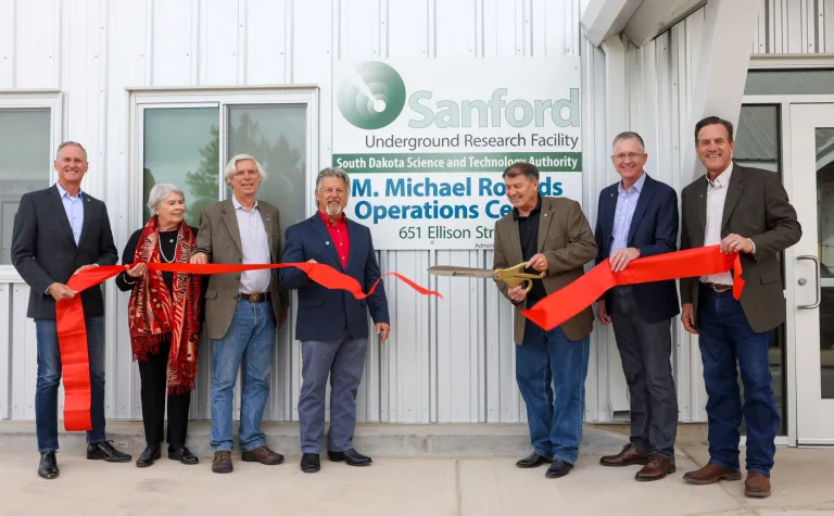 people hold a ribbon that has just been cut