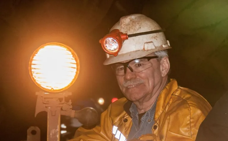 Stratton smiles next to the headlight of a motorcar