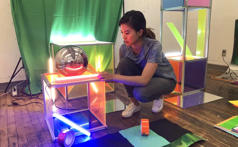 an artist kneels beside an unfinished exhibit