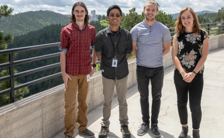 Four students stand outside 