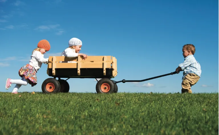 Kids pushing and pulling on a wagon.