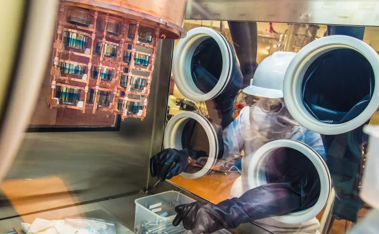 A researcher works on a cryostat inside a glovebox.