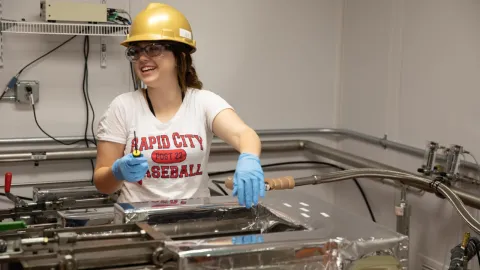 a student in the BHSU underground lab smiling while doing research in PPE. 