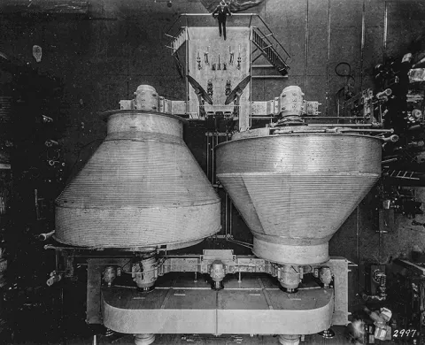 "The Nordberg Manufacturer’s double drum hoist is shown from above. The diameter at one end is 25 feet and tapers to a diameter of 12 feet at the other end, allowing them to sit opposite each other and shrink the footprint of the drums. Courtesy Siemag Tecberg, Inc." image "black and white photo of…ists aligned from above"