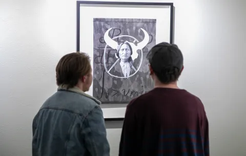 Two people look at one of Marty Two Bulls' works at the Ruddell Gallery. 