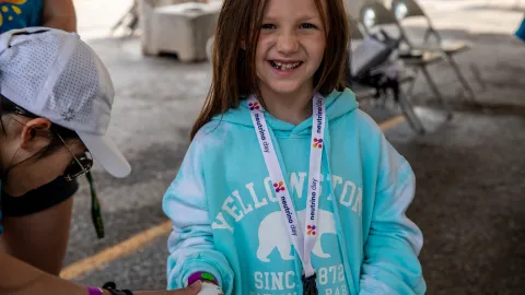 A child smiles while getting a tempoary Neutrino Day Tattoo. 