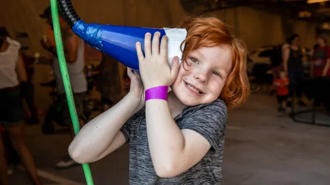 A child listens to a device brought by Little Shop of Physics during the Neutrino Day 2024 event. 