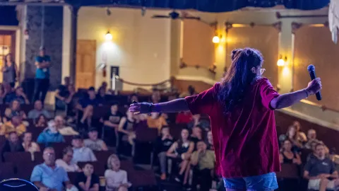 A presenter spreading her arms in front of the crowd at the Homestake Opera House 