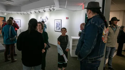 People speak with Marty Two Bulls at the artist reception in the Ruddell Gallery