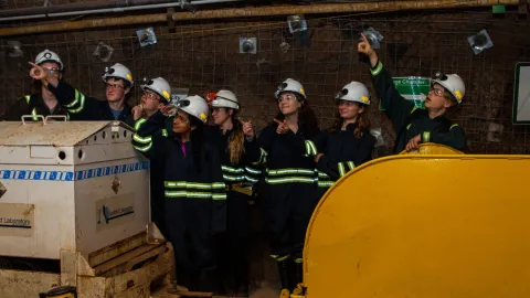 students stand underground pointing into the middle distance